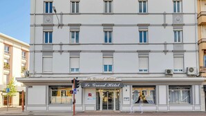 Un hotel de varios pisos con fachada clásica, ventanas amplias y un letrero que dice "Le Grand Hotel".
