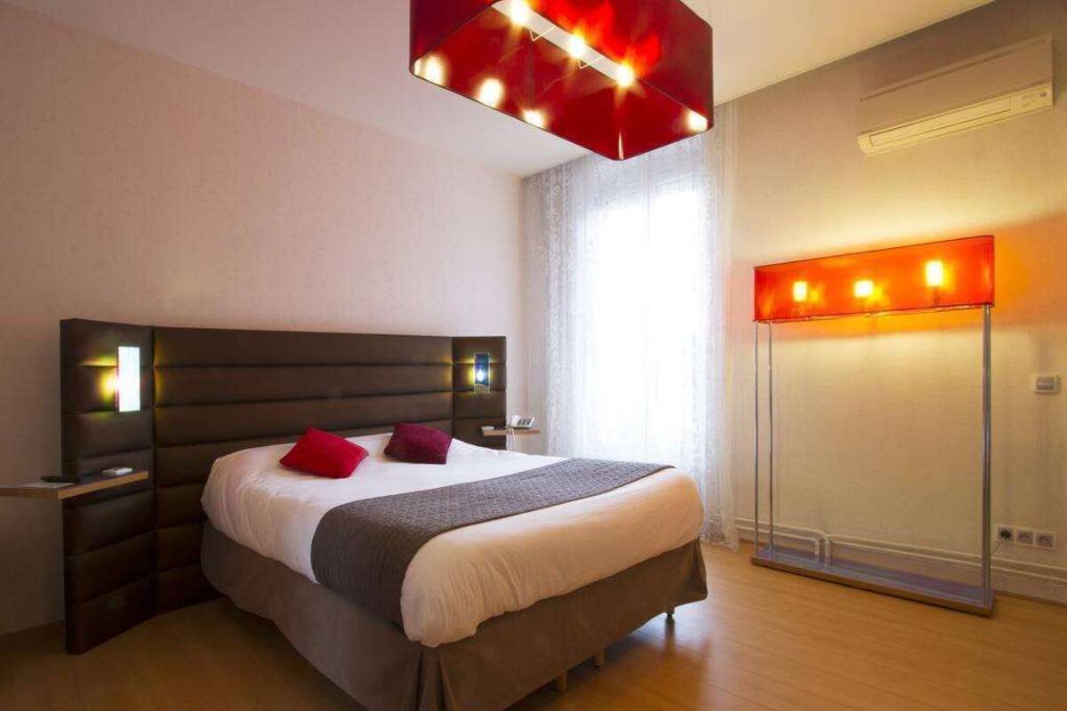 Une chambre moderne avec un grand lit, des tables de chevet, une armoire et un luminaire au plafond.