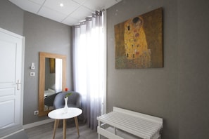 Una habitación moderna con un espejo grande, un banco blanco y un cuadro en la pared.