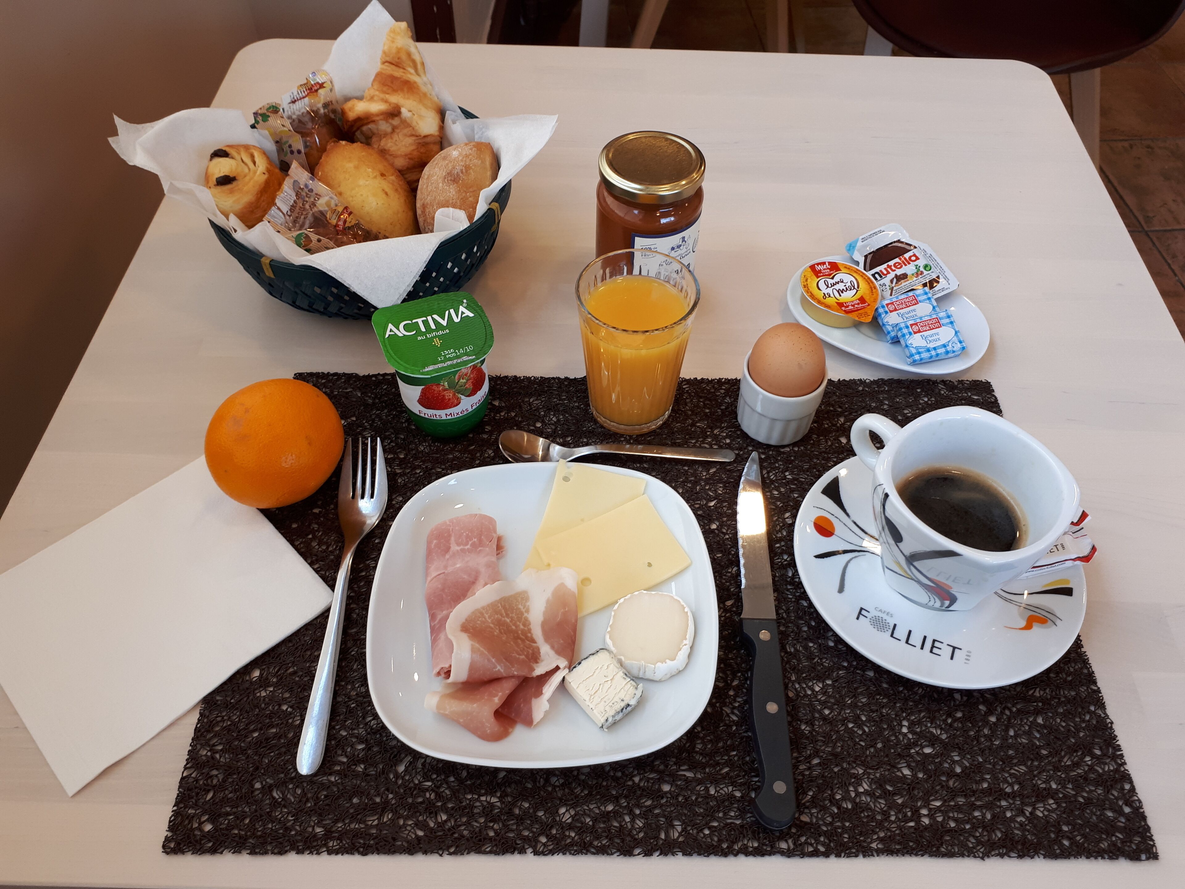 Uma mesa de café da manhã com diversos alimentos, incluindo pão, ovos, queijo e uma xícara de café.