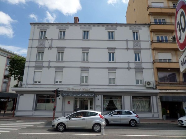 A multi-story hotel with a classic facade, a ground-floor entrance, and a visible sign for 'Le Grand Hotel'.