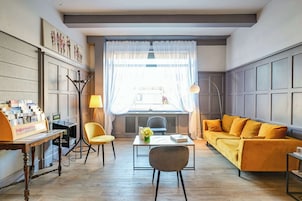 Un soggiorno moderno con un divano, poltrone, un tavolino da caffè e una scrivania con un cartello.