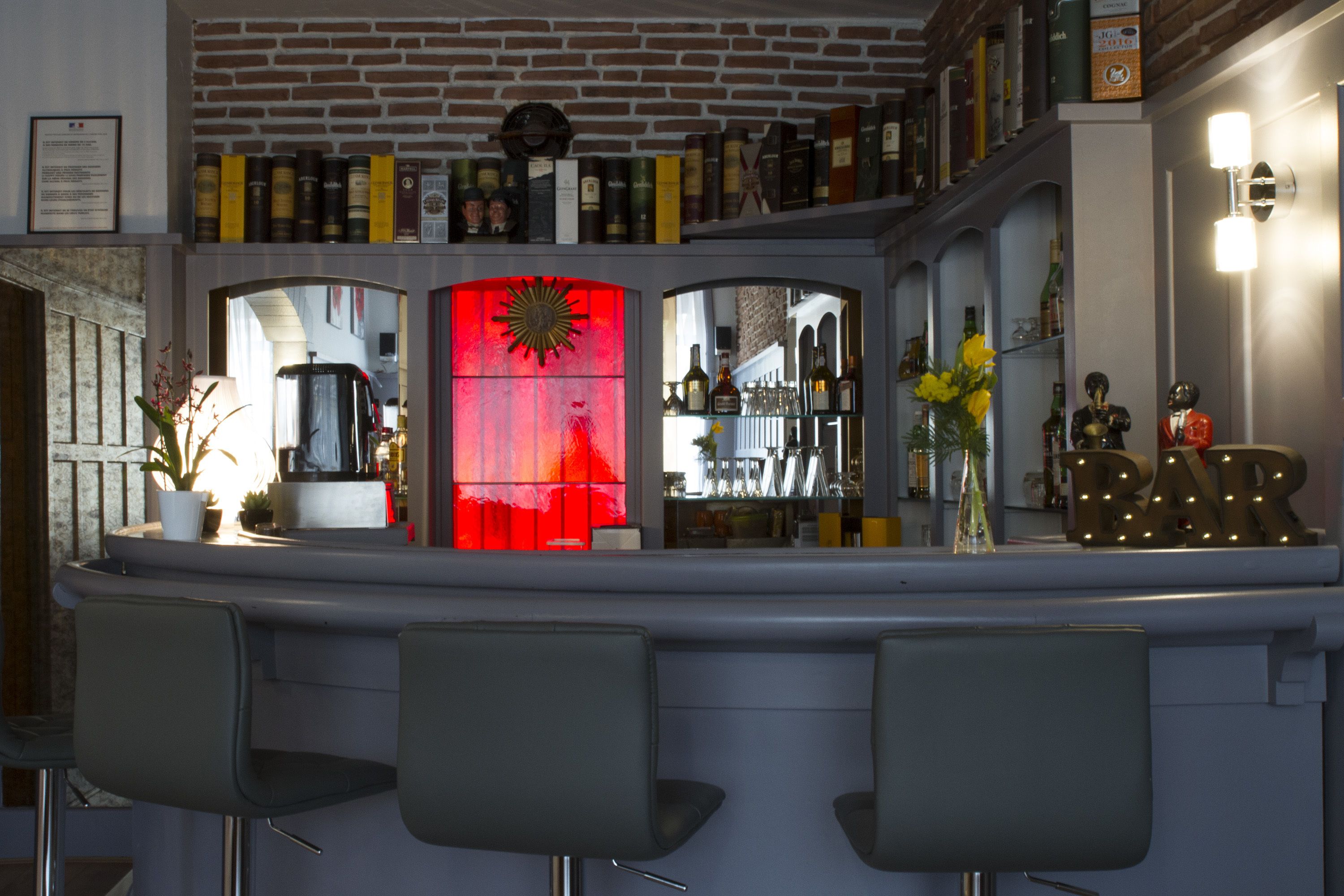 A bar area with a red-lit partition, shelves with bottles, and a 'BAR' sign.