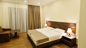Una habitación de hotel con cama, mesita de noche, lámpara y una silla.