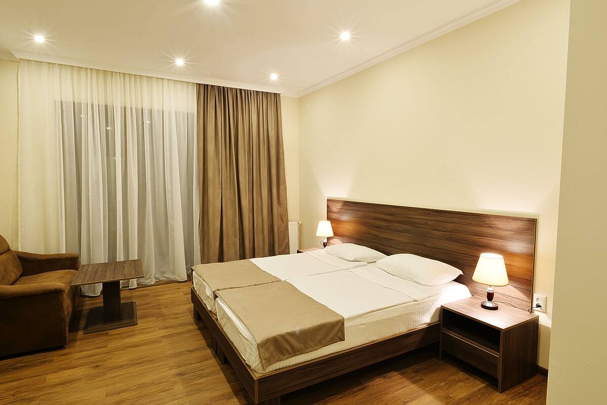 A hotel room with a bed, bedside table, lamp, and a chair.