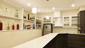 Una cocina moderna con armarios blancos, una encimera de mármol y varias botellas y recipientes en las estanterías.