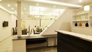 Un interior moderno con una escalera, una zona de comedor y una zona de bar con estantes llenos de botellas.