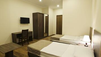 A hotel room with two beds, a desk, a chair, a TV, and a wardrobe.