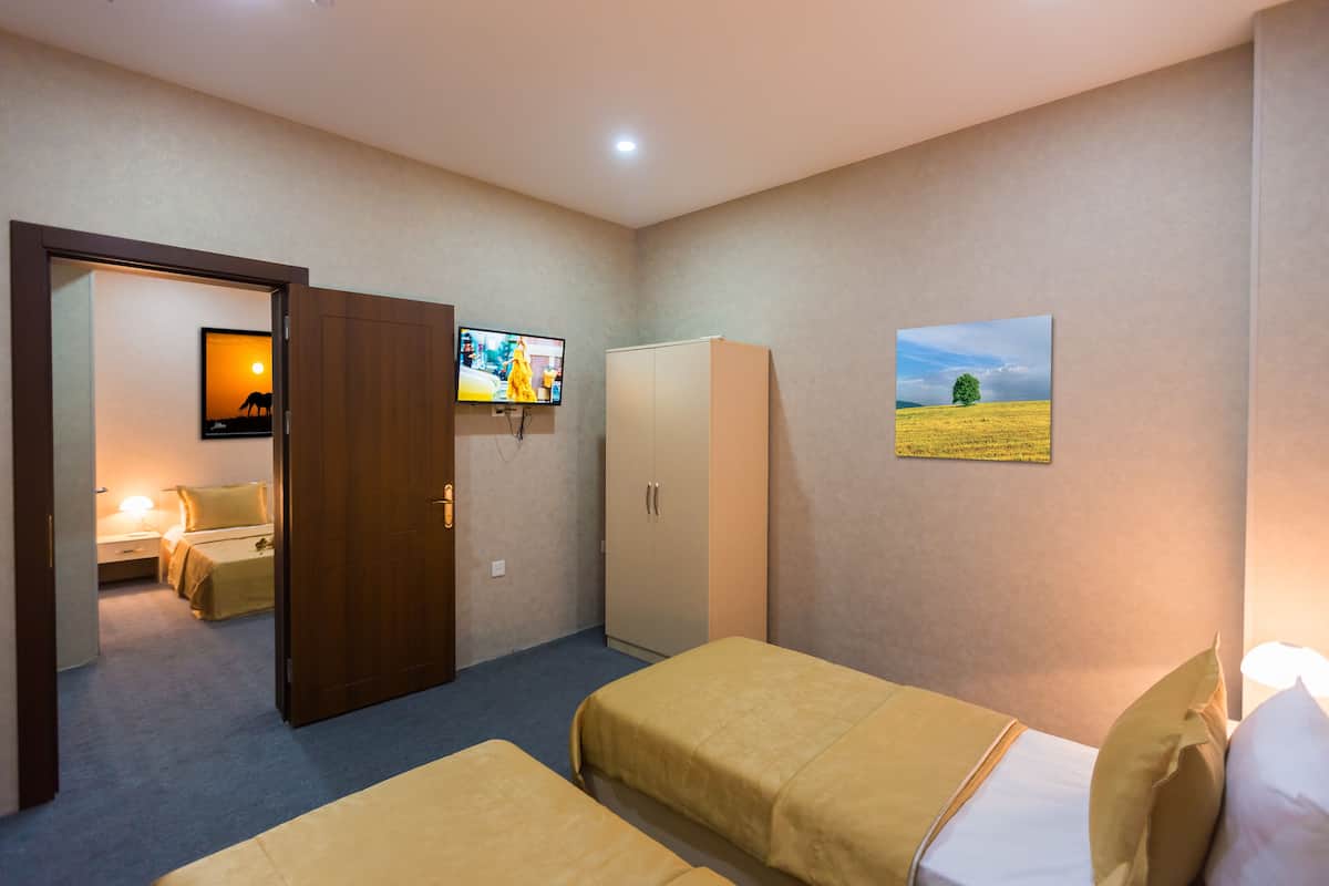 Une chambre d’hôtel avec deux lits, une armoire, un téléviseur et un tableau au mur.