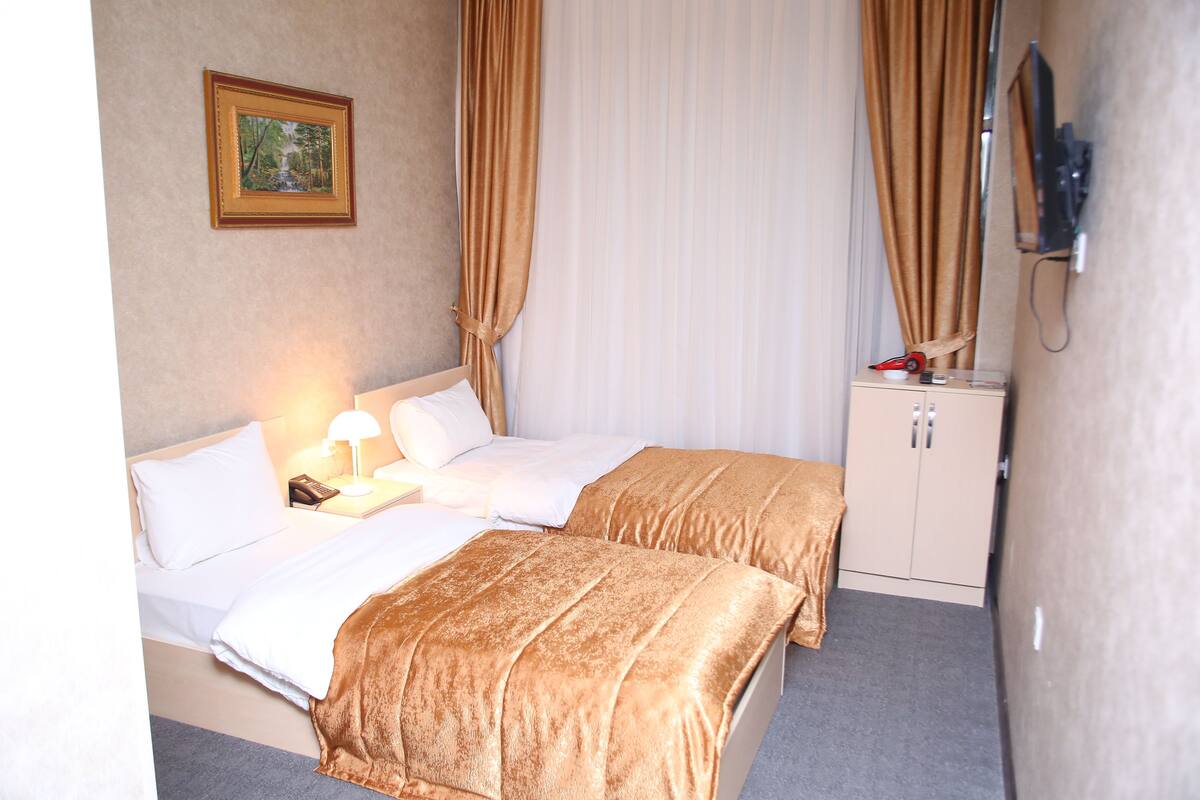 Une chambre d’hôtel avec deux lits, une table de chevet avec une lampe, une armoire et un tableau au mur.