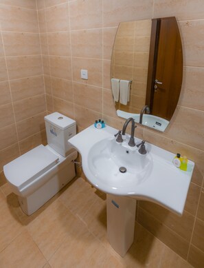 A bathroom with a toilet, bidet, sink, and mirror. - Riva Hotel (Baku)