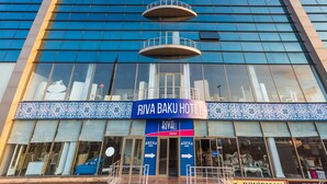 The exterior of Riva Bakı Hotel with a modern glass facade, multiple balconies, and a blue and white patterned entrance. - Riva Hotel (Baku)