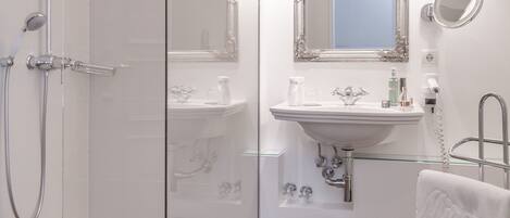 A modern bathroom with a glass shower enclosure, a sink with a mirror above it, and a towel rack.