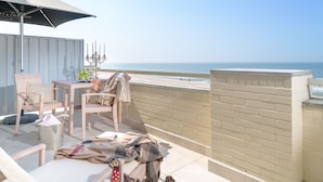 Un balcón con mobiliario de mimbre, una mesa y vista al mar.