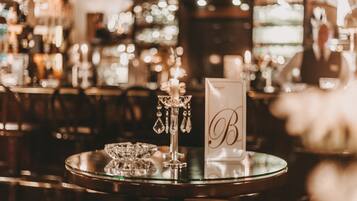 A bar area with a round table featuring a candle holder and a sign with the letter "B".