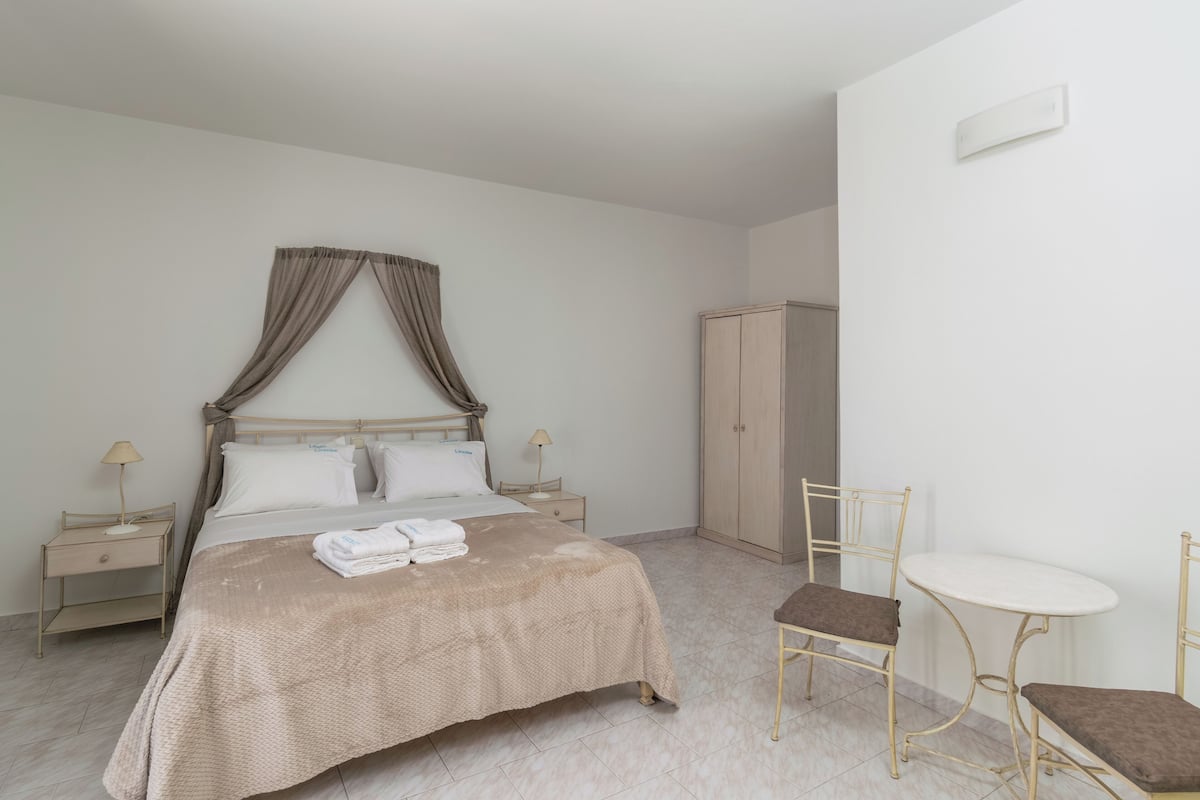 A bedroom with a bed, bedside tables, a wardrobe, and a small round table with chairs.