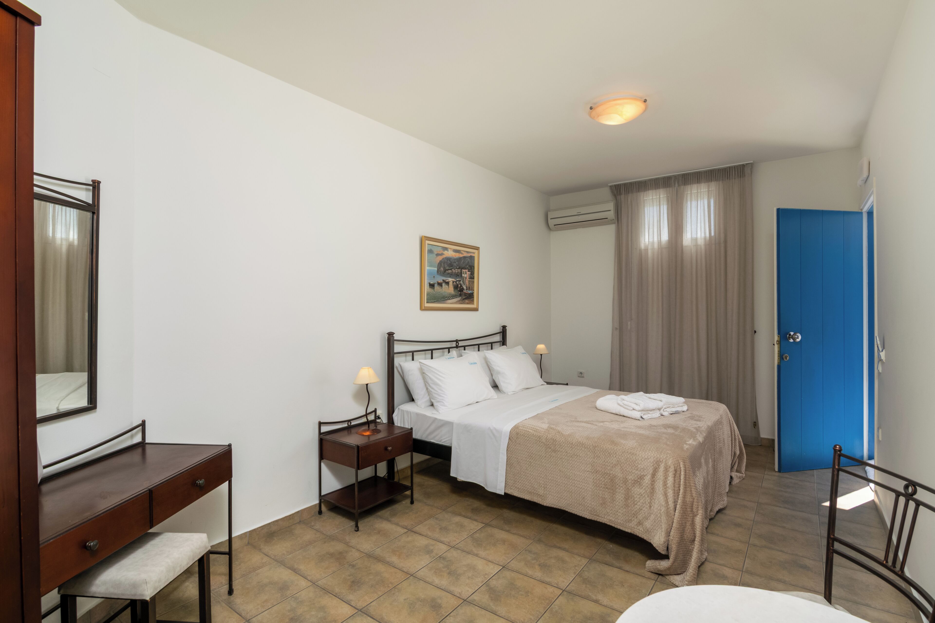 A bedroom with a bed, bedside table, lamp, and a blue door.
