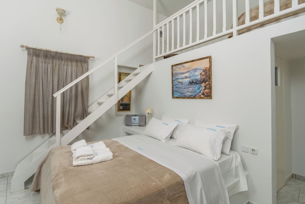 A hotel room with a bed, a painting, a staircase, and a control panel.