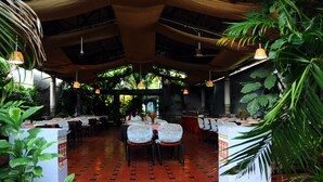 An indoor dining area with tables and chairs, a patterned floor, and hanging lights. - KSTDC Hotel Mayura Bhuvaneshwari (Hospet)