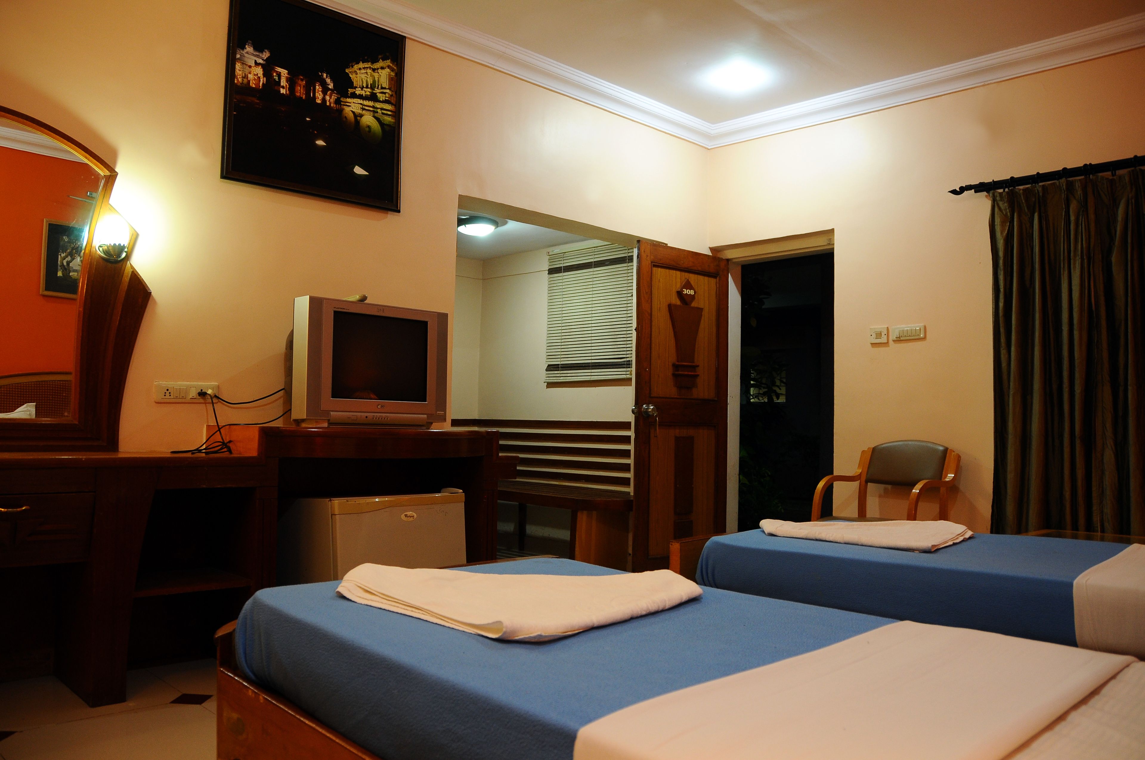 A hotel room with two beds, a desk with a computer, a television, and a chair.