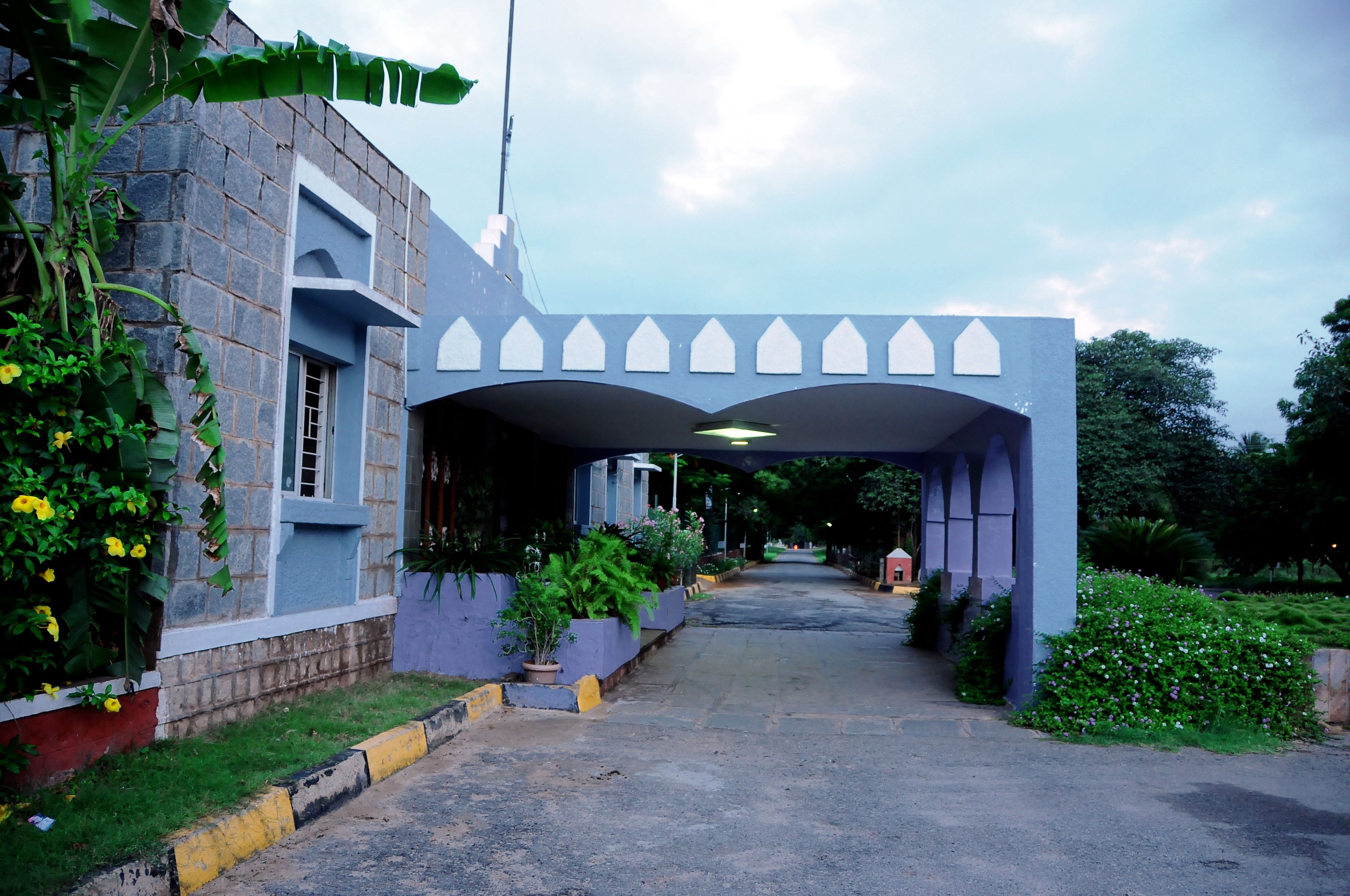 A building with a blue facade, a covered entrance, and a pathway leading to the entrance.
