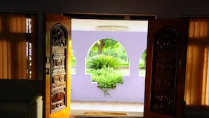 An open door leading to a garden with a view of greenery and a tree. - KSTDC Hotel Mayura Bhuvaneshwari (Hospet)