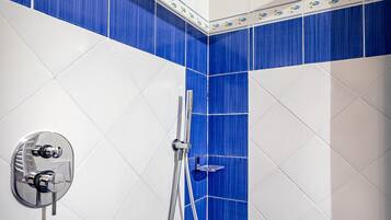 A bathroom with blue and white tiles, a showerhead, and a faucet.