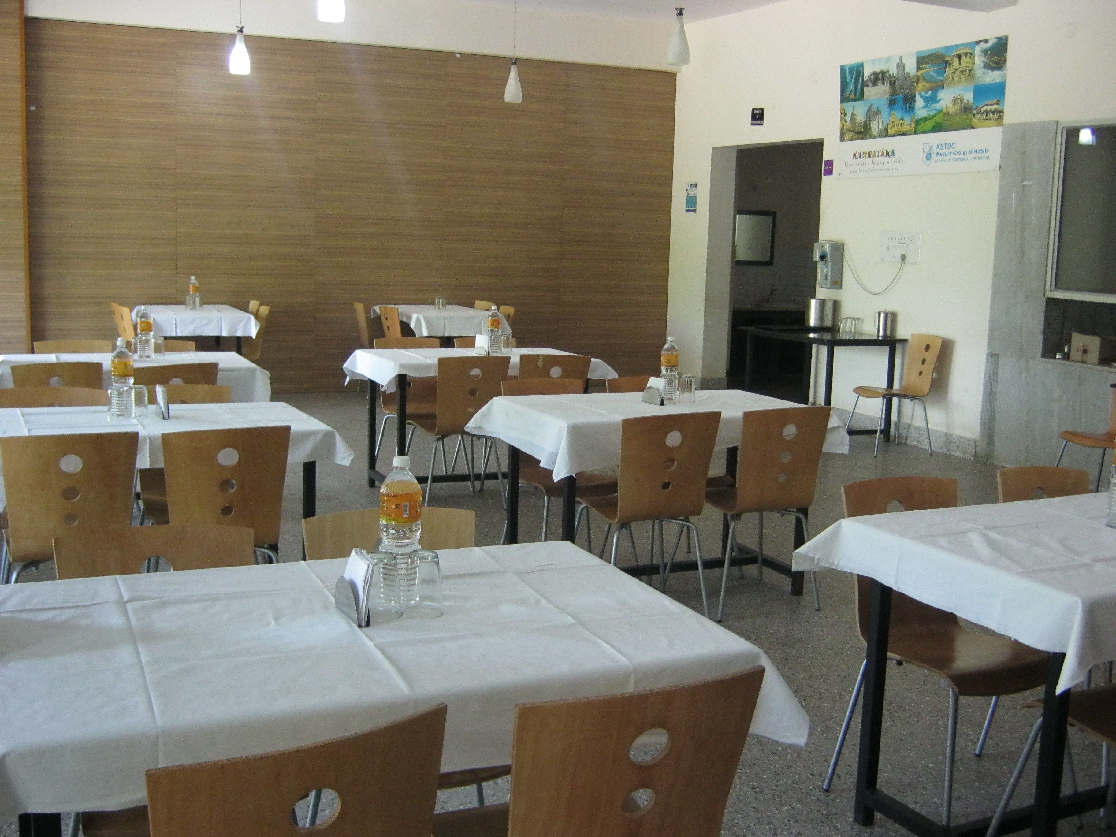 Un comedor con varias mesas y sillas, una pared de madera y un televisor.