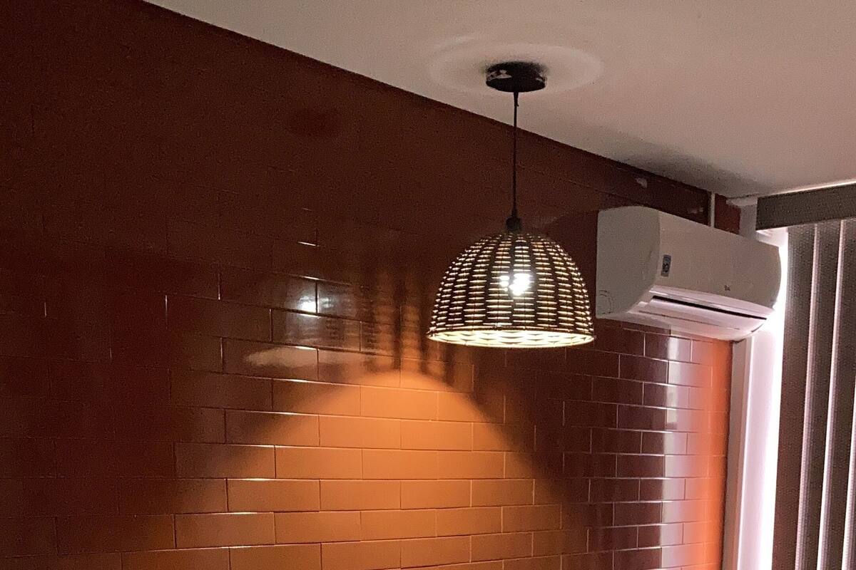 Ein Hotelzimmer mit Backsteinwand, einem Bett, einem Sessel, einem kleinen Tisch und einer Pendelleuchte.