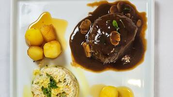 Un plato cuadrado con un guiso de carne, patatas y arroz.