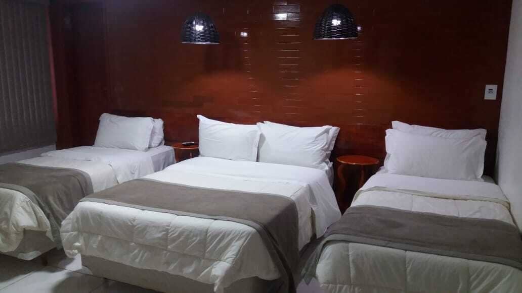 Ein Hotelzimmer mit zwei Einzelbetten, einem Holzkopfteil und zwei Nachttischen.
