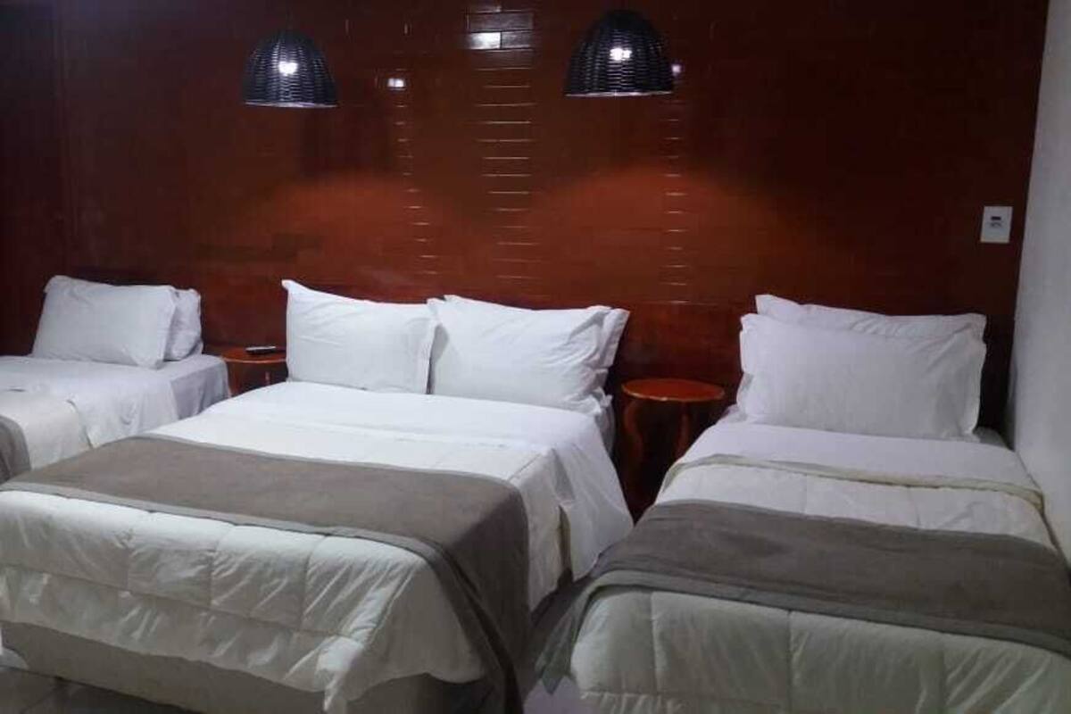 Ein Hotelzimmer mit zwei Einzelbetten, einem Holzkopfteil und zwei Nachttischen.