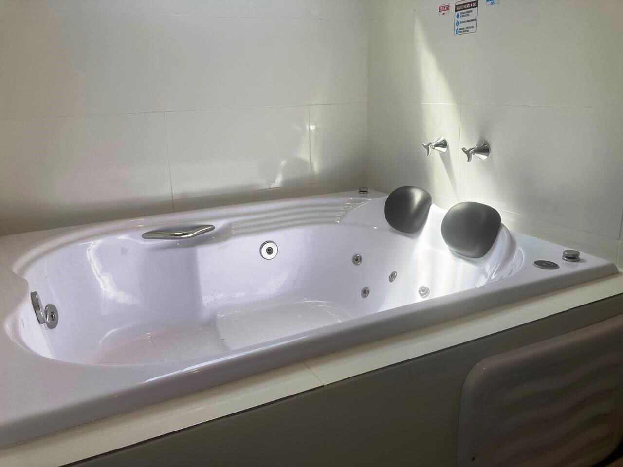 A white bathtub with a built-in seat and controls, a showerhead, and a drain.