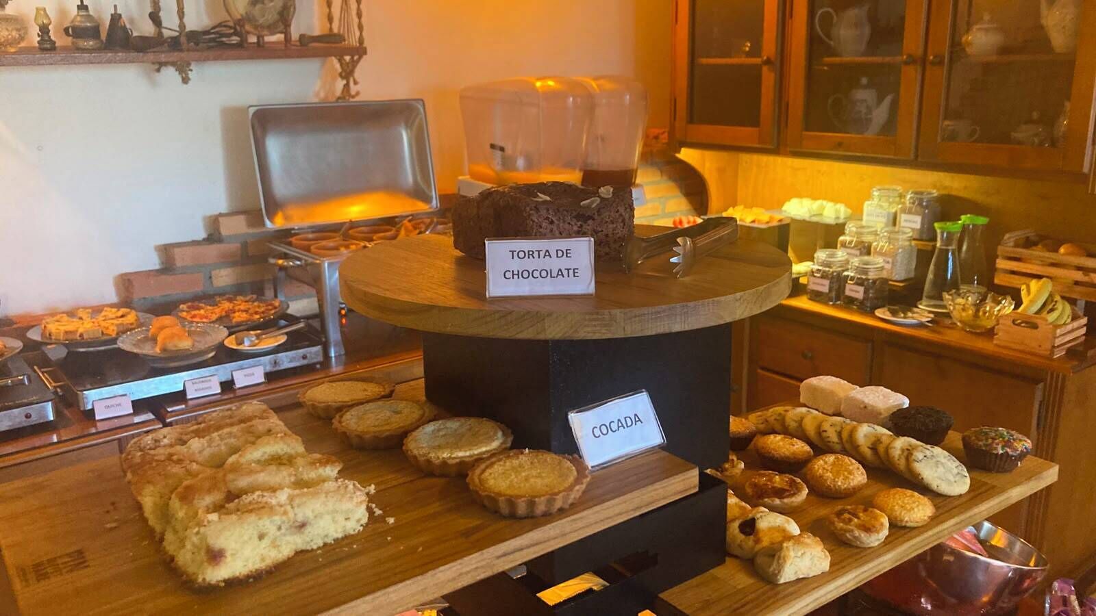 Una vitrina de panadería con diversos productos horneados, incluyendo un letrero que dice 'TORTA DE CHOCOLATE' y 'COCADA'.