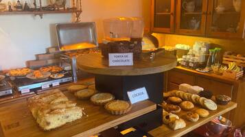 Una vitrina de panadería con diversos productos horneados, incluyendo un letrero que dice 'TORTA DE CHOCOLATE' y 'COCADA'.