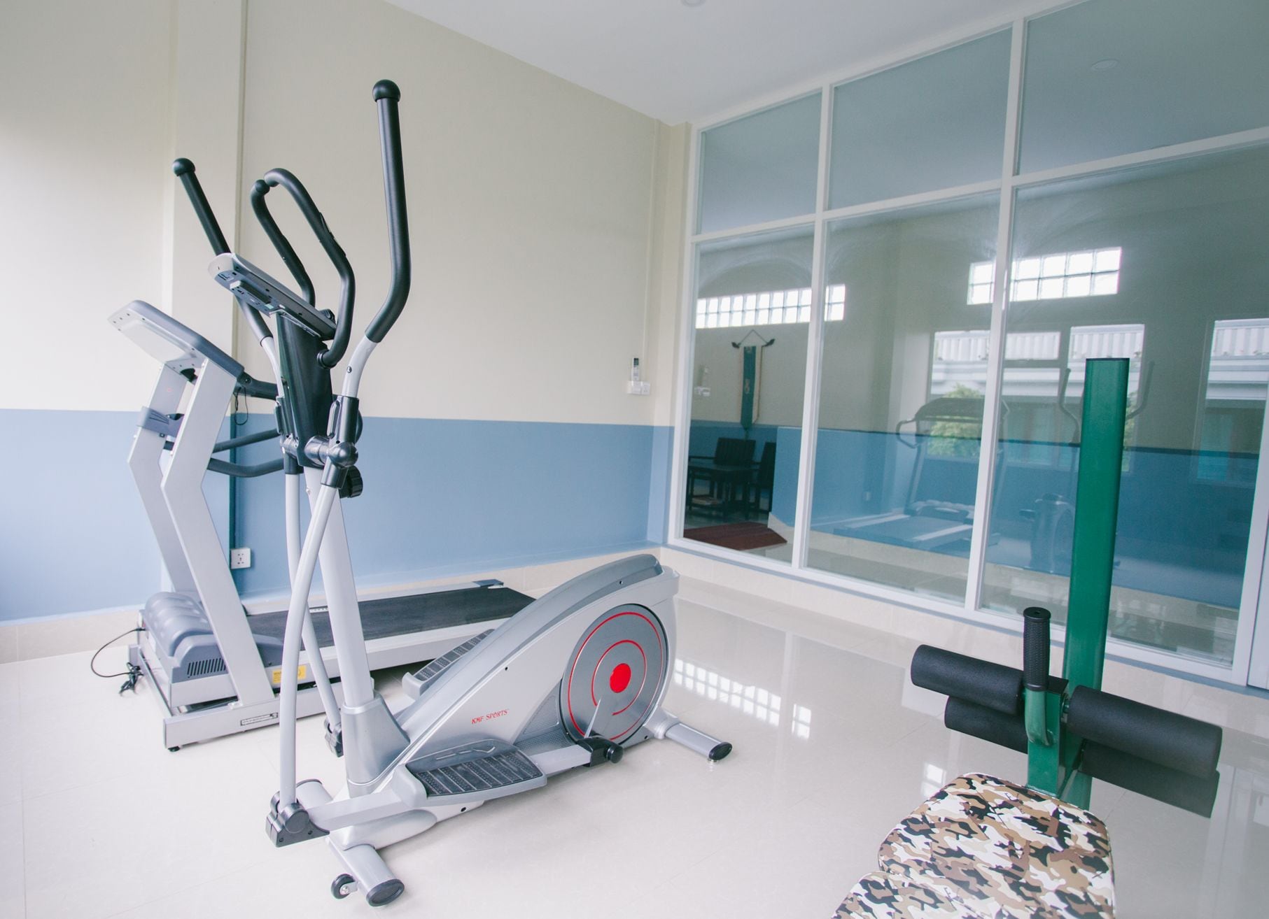 Un gimnasio con máquinas de cardio, un espejo grande y vistas al exterior.