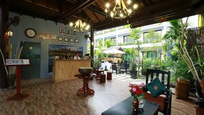 Un restaurante interior con suelo de madera, una recepción y vistas al jardín exterior.
