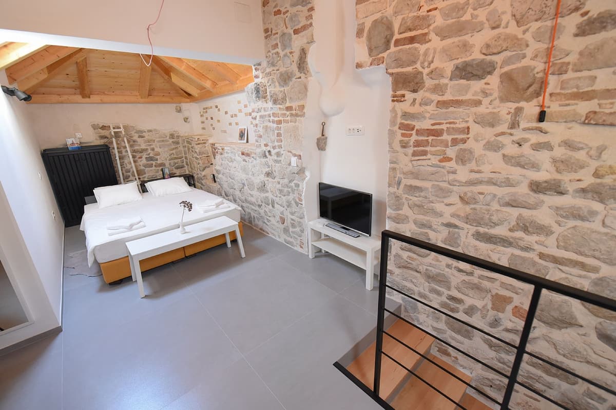 Ein Schlafzimmer mit Steinsturz, Bett, Fernseher und Holzboden.