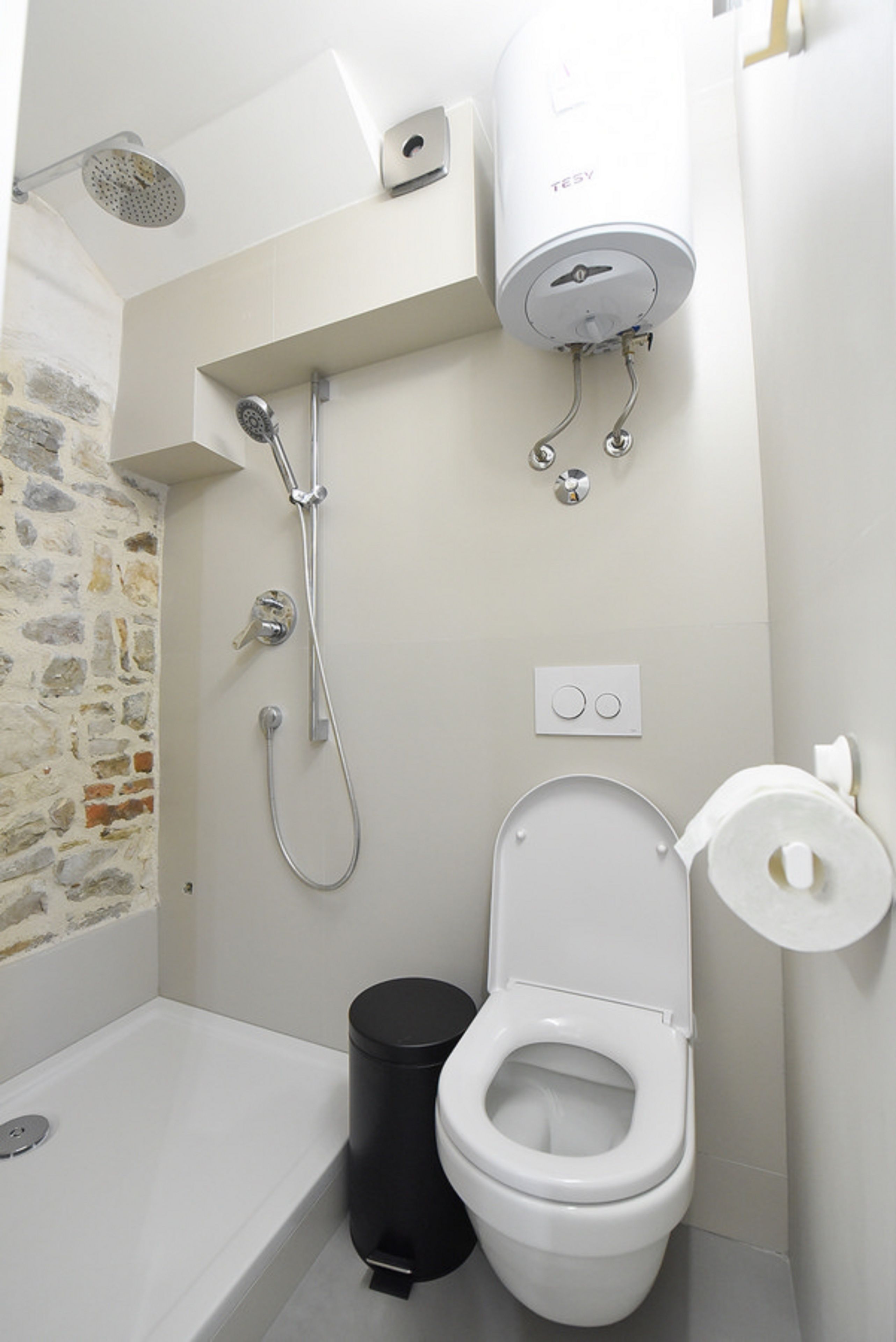 Un bagno piccolo ma funzionale, con doccia, WC e cestino.