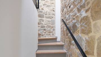 Una escalera con escalones de madera y un muro de piedra a un lado.