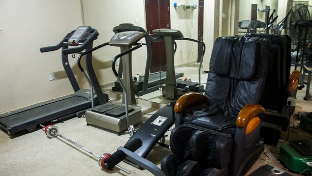 A gym with exercise equipment including treadmills, a weight bench, and a massage chair. - De' Bliss Hotel and Suites (Lagos)