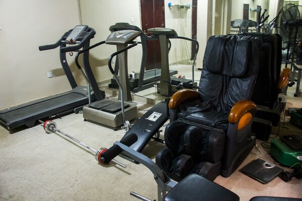 A gym with exercise equipment including treadmills, a weight bench, and a massage chair. - De' Bliss Hotel and Suites (Lagos)