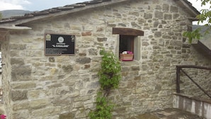 Ein Steinhaus mit einer Schildtafel, auf der 'Agriturismo Il Casalone' steht.