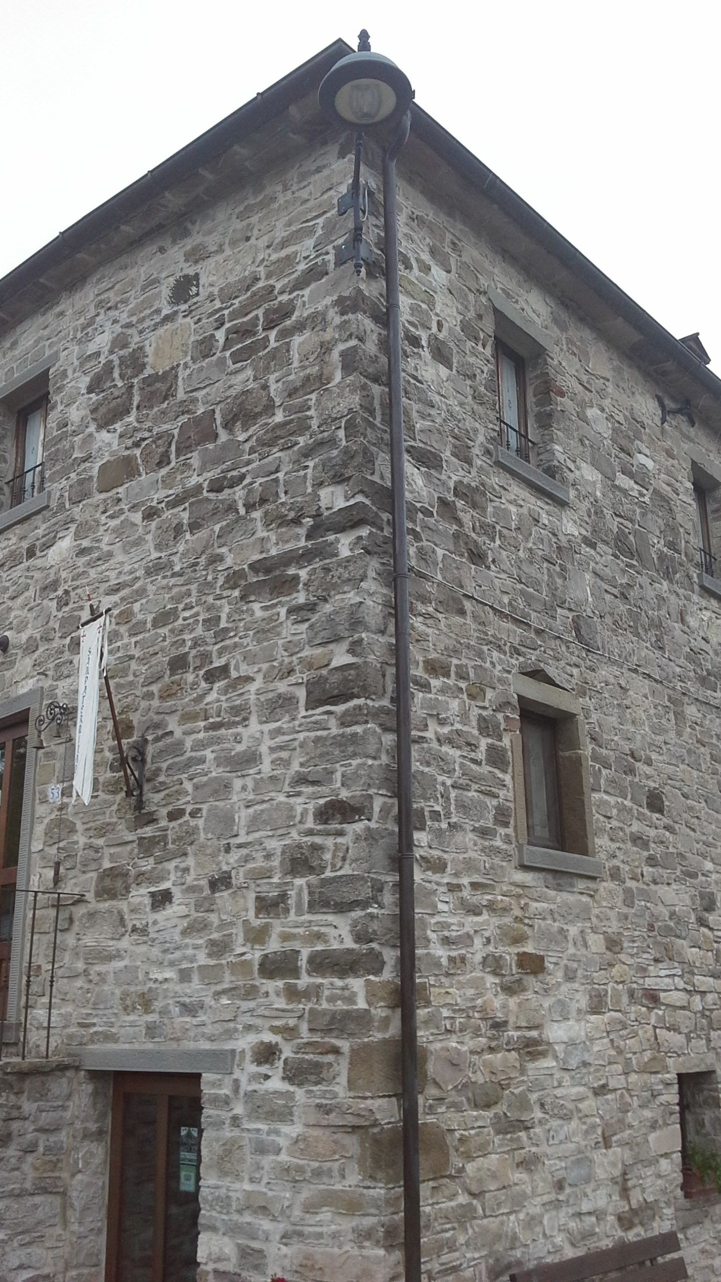 A stone building with a corner entrance, a visible door, and a window.