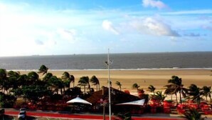 Vista de playa con palmeras y cielo despejado.