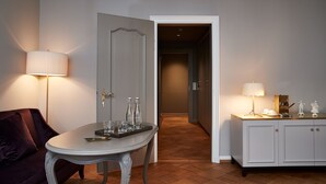 Una habitación con una mesa, un sofá, un armario y una puerta que da a otra estancia.