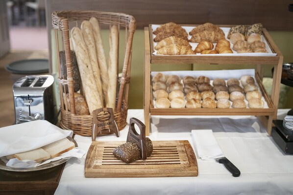 Una vitrina de panadería con diversos panes y pasteles, un tostador y una tabla de cortar con un cuchillo.