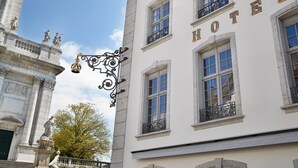 Un hotel con fachada clásica, ventanas amplias y un cartel con su nombre.