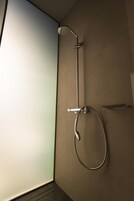 A shower with a handheld showerhead and a handheld shower attachment.