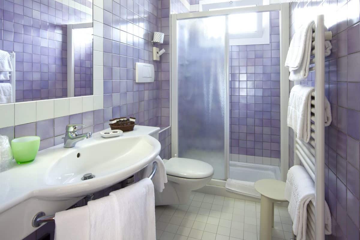 A modern bathroom with a large mirror, a sink, a toilet, and a shower area.
